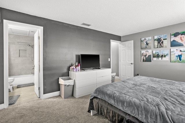 bedroom with ensuite bath, light carpet, and a textured ceiling