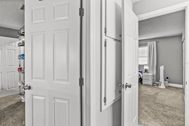 corridor with carpet floors and a textured ceiling