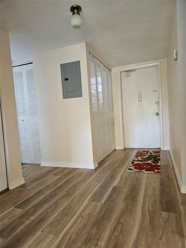 hallway featuring wood-type flooring, a textured ceiling, and electric panel