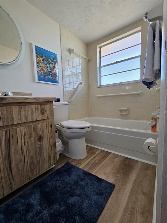 full bathroom with vanity, a textured ceiling, hardwood / wood-style floors, toilet, and tiled shower / bath