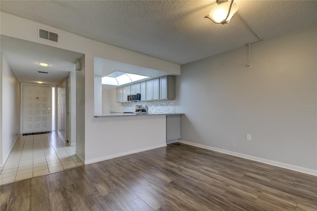 kitchen featuring a textured ceiling, backsplash, stainless steel range with electric cooktop, and dark hardwood / wood-style floors