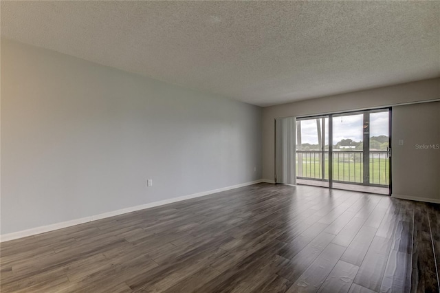 empty room with dark wood-type flooring and a textured ceiling