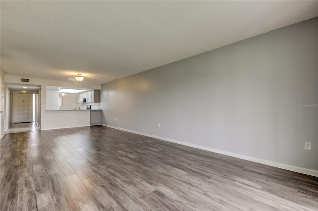 unfurnished living room with hardwood / wood-style floors and a textured ceiling