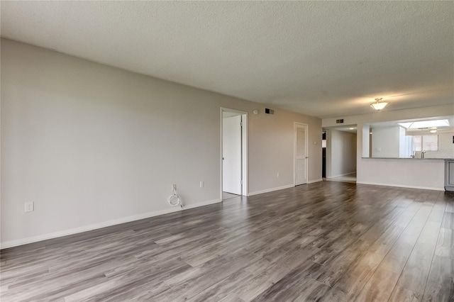 unfurnished living room featuring wood-type flooring, a textured ceiling, and sink