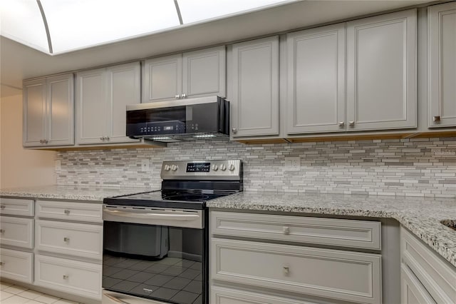 kitchen with backsplash, light stone counters, stainless steel electric stove, and light tile patterned flooring