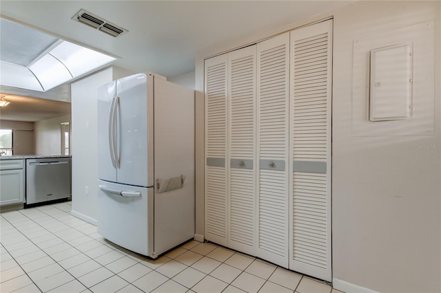 kitchen featuring light tile patterned flooring, white cabinets, white fridge, and stainless steel dishwasher