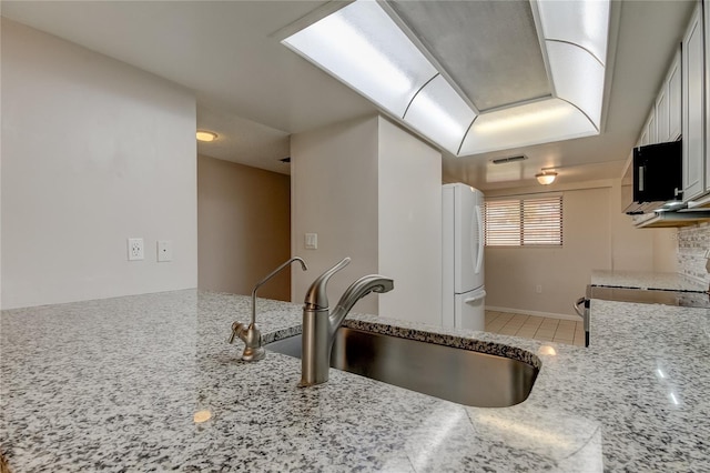 kitchen featuring stove, light stone counters, sink, white refrigerator, and white cabinets