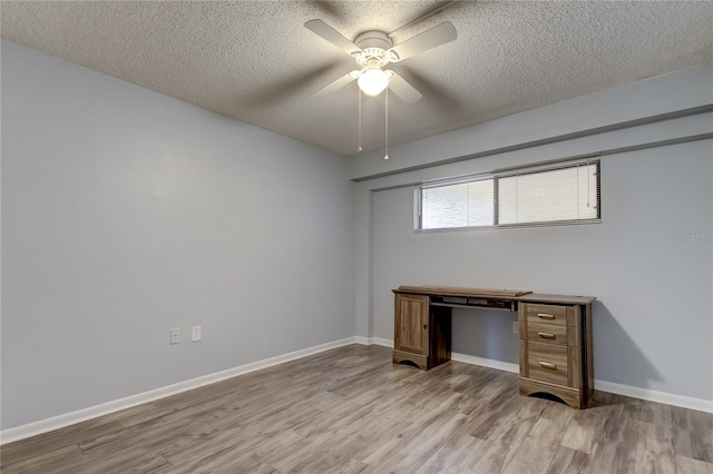 unfurnished office with ceiling fan, light wood-type flooring, and a textured ceiling