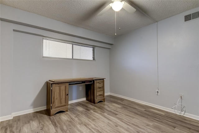 unfurnished office with ceiling fan, light hardwood / wood-style flooring, and a textured ceiling