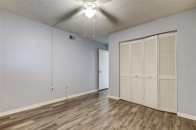 unfurnished bedroom with ceiling fan, a closet, light hardwood / wood-style floors, and a textured ceiling