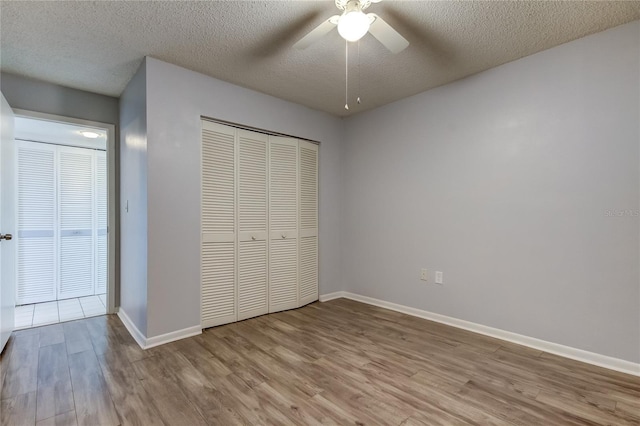 unfurnished bedroom featuring a closet, a textured ceiling, light hardwood / wood-style floors, and ceiling fan