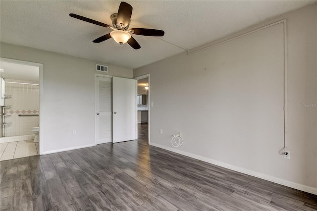 unfurnished bedroom featuring dark hardwood / wood-style flooring, a textured ceiling, ceiling fan, connected bathroom, and a closet