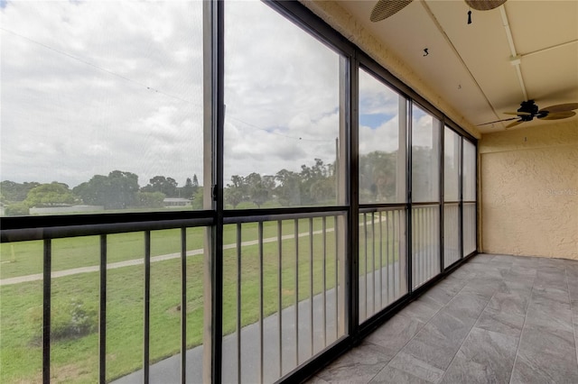 unfurnished sunroom featuring ceiling fan and plenty of natural light