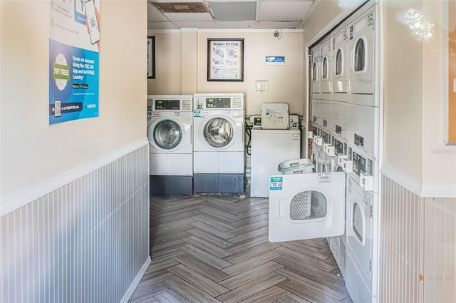 clothes washing area featuring stacked washer and clothes dryer, parquet flooring, and washer and clothes dryer