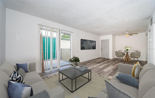 living room featuring a textured ceiling, ceiling fan, and light hardwood / wood-style floors