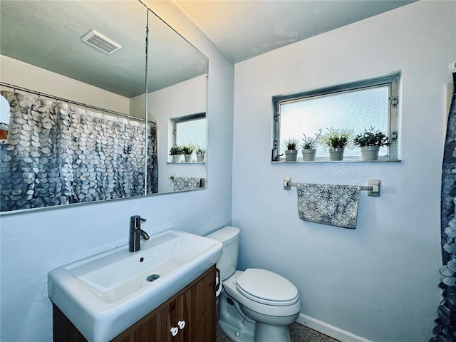 bathroom with vanity, toilet, and a wealth of natural light