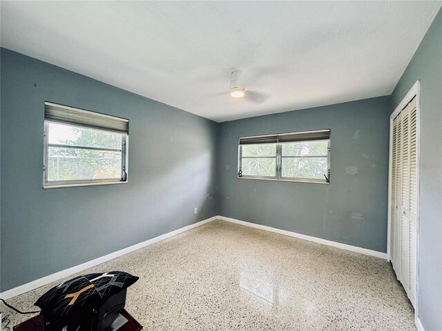 unfurnished bedroom featuring multiple windows, ceiling fan, and a closet