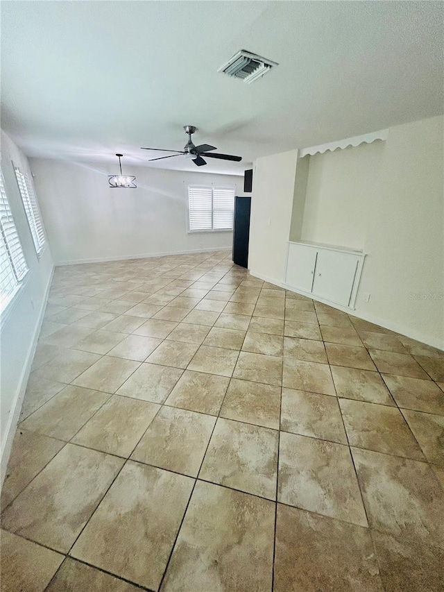 unfurnished room with light tile patterned flooring and ceiling fan with notable chandelier