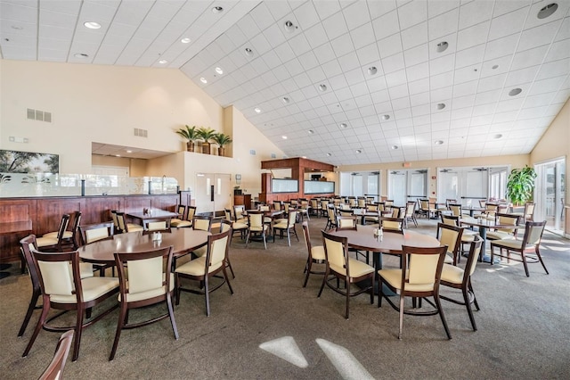 dining area with dark colored carpet and a high ceiling