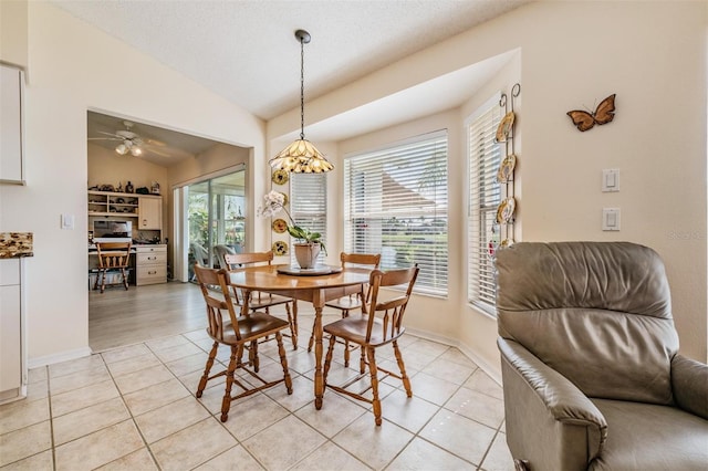 tiled dining room with ceiling fan, a textured ceiling, and vaulted ceiling