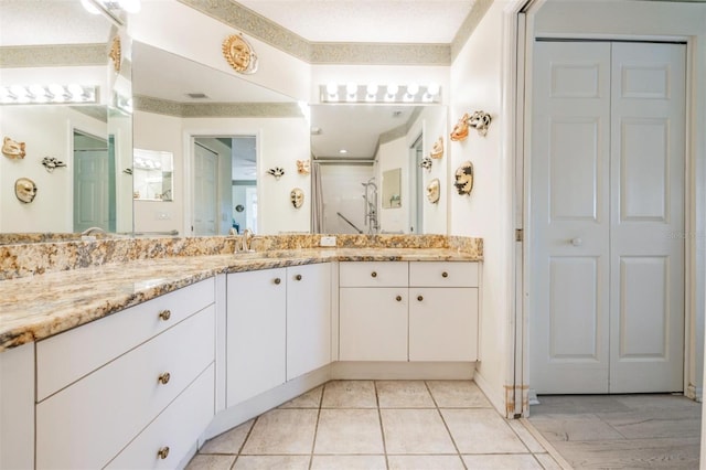 bathroom featuring vanity, a shower, a textured ceiling, and tile patterned flooring