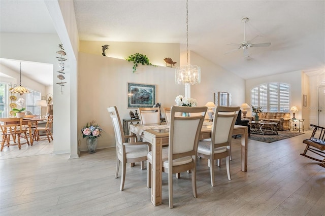 dining area featuring light hardwood / wood-style floors, ceiling fan with notable chandelier, lofted ceiling, and a healthy amount of sunlight