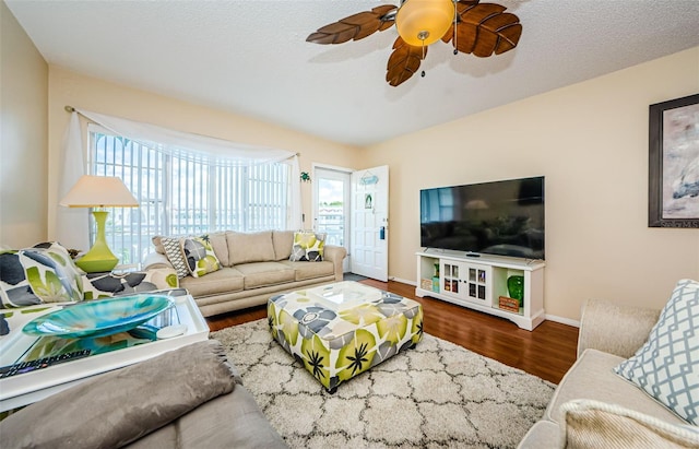 living room with dark hardwood / wood-style floors, ceiling fan, and a textured ceiling