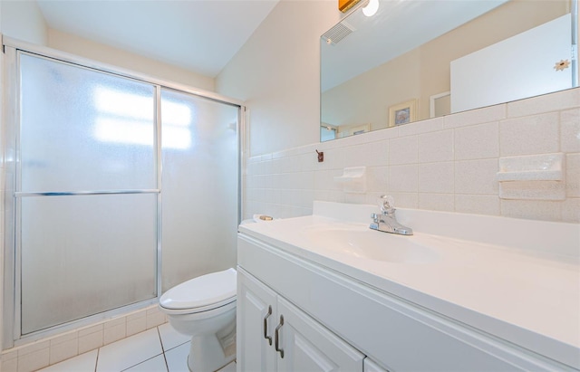 bathroom featuring tile patterned floors, vanity, a shower with door, tile walls, and toilet