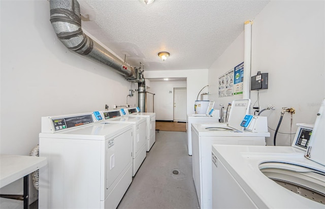 washroom with a textured ceiling, electric water heater, and washer and clothes dryer