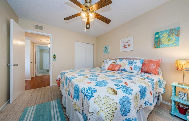 bedroom with ceiling fan, a closet, light hardwood / wood-style floors, and a textured ceiling