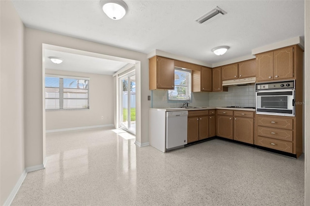 kitchen featuring tasteful backsplash, oven, sink, dishwasher, and gas cooktop