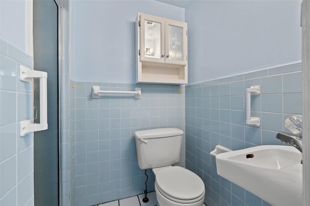 bathroom featuring tile patterned floors, sink, tile walls, and toilet