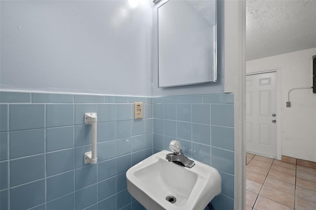 bathroom with sink, tile walls, tile patterned floors, and a textured ceiling