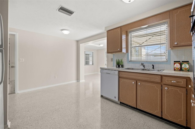 kitchen with plenty of natural light, sink, dishwasher, and backsplash