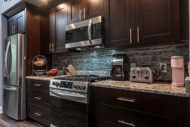 kitchen with light stone countertops, appliances with stainless steel finishes, backsplash, dark brown cabinetry, and dark hardwood / wood-style floors