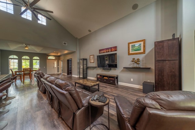 living room with ceiling fan, a towering ceiling, and dark hardwood / wood-style floors