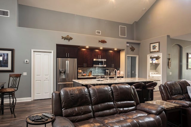 living room featuring washer / clothes dryer, high vaulted ceiling, dark wood-type flooring, and sink