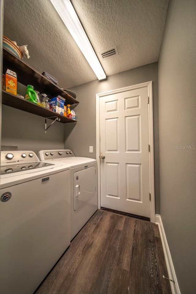 clothes washing area with dark hardwood / wood-style flooring, independent washer and dryer, and a textured ceiling