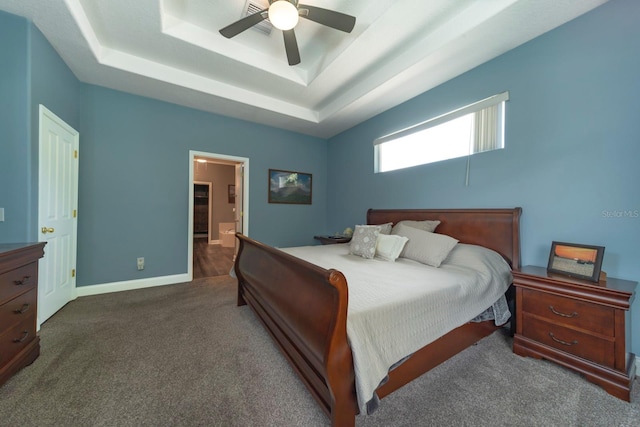 bedroom featuring dark colored carpet, ceiling fan, and a tray ceiling