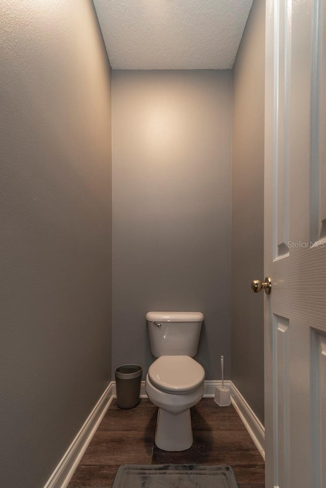 bathroom featuring a textured ceiling, hardwood / wood-style flooring, and toilet