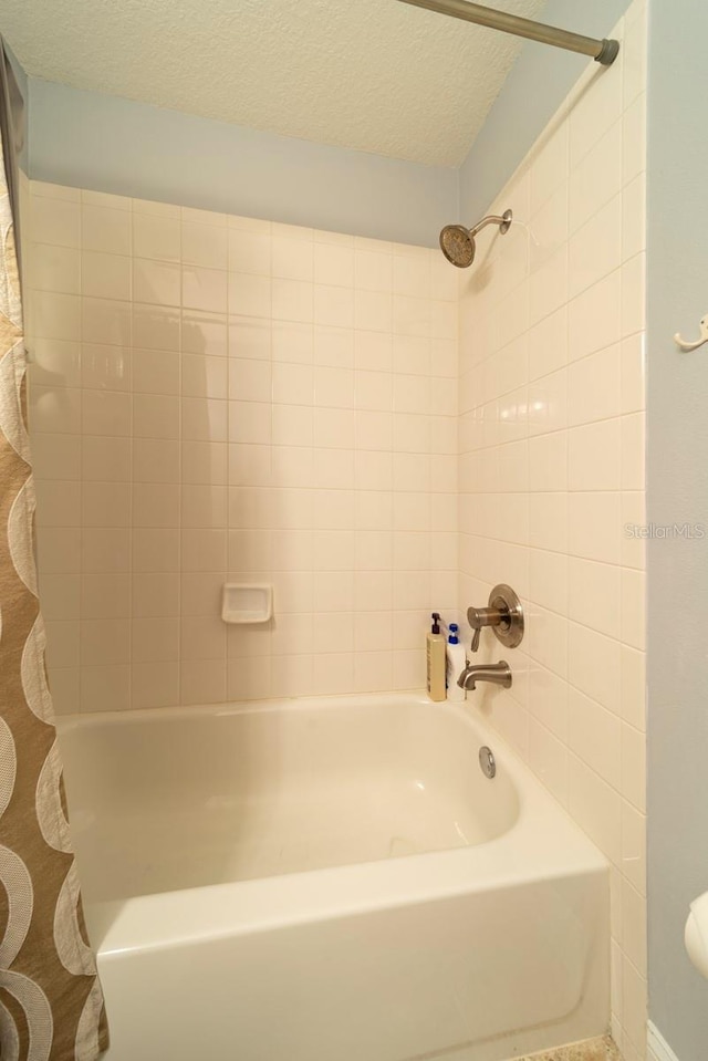 bathroom with shower / bath combination with curtain and a textured ceiling