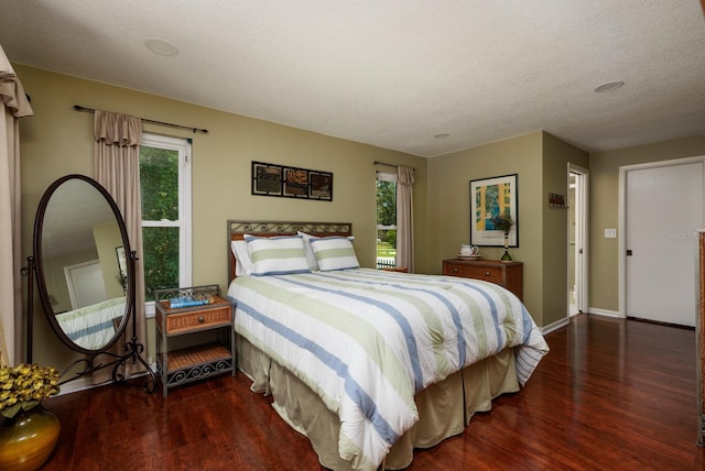 bedroom featuring dark hardwood / wood-style floors, a textured ceiling, and multiple windows