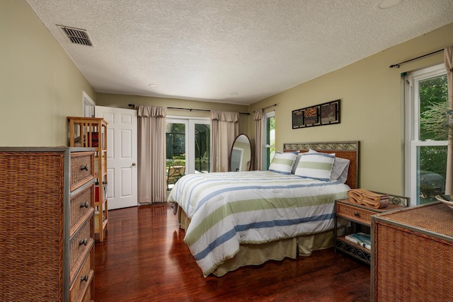 bedroom with access to exterior, a textured ceiling, and dark wood-type flooring