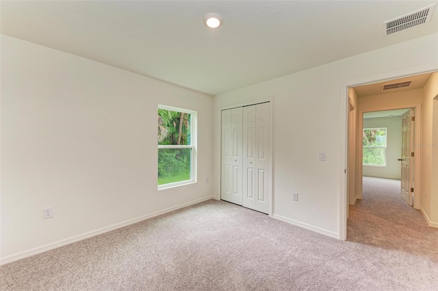 unfurnished bedroom with a closet and light colored carpet