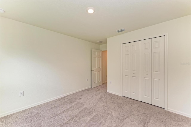 unfurnished bedroom with a closet and light colored carpet