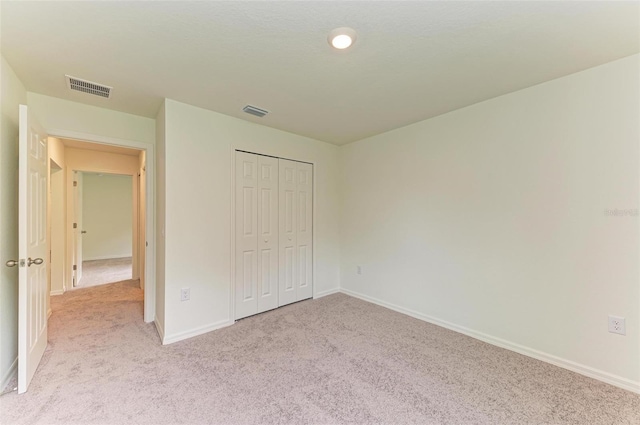 unfurnished bedroom with light colored carpet and a closet