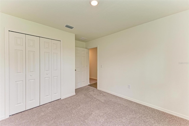 unfurnished bedroom with light carpet and a closet