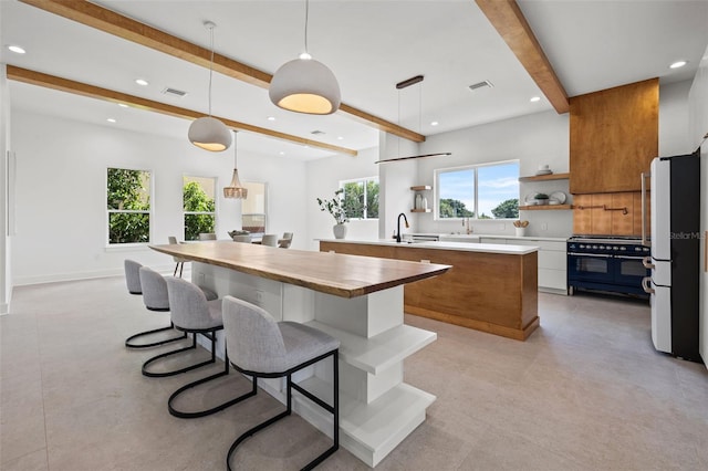 kitchen with white fridge, beam ceiling, hanging light fixtures, and gas range