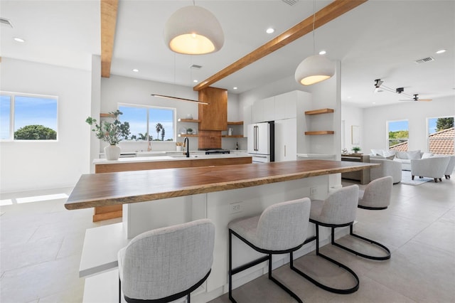 kitchen with pendant lighting, ceiling fan, high end white fridge, and white cabinetry