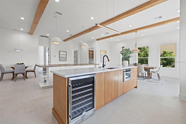 kitchen with beam ceiling, a spacious island, hanging light fixtures, and beverage cooler